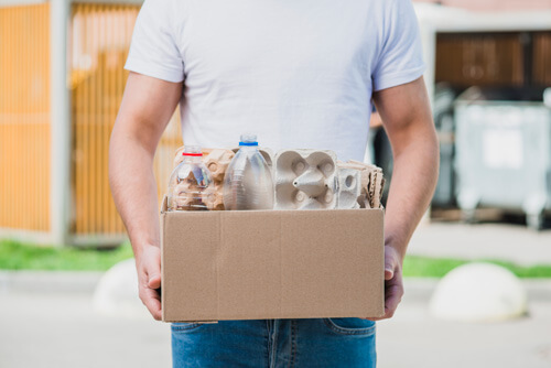 Foto hombre con caja decartón que lleva materilaes reciclados